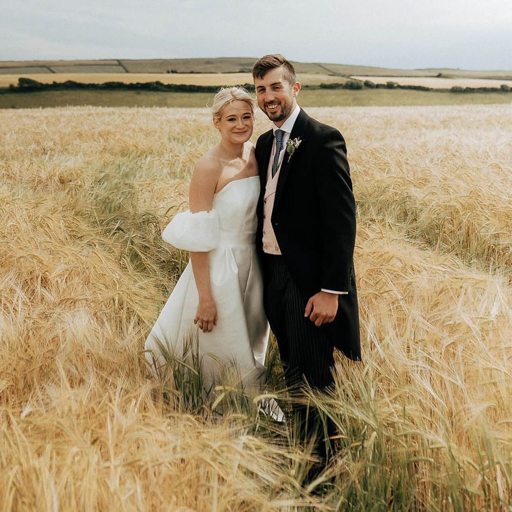 Bride and groom walk through golden fields during couples portraits outdoors 