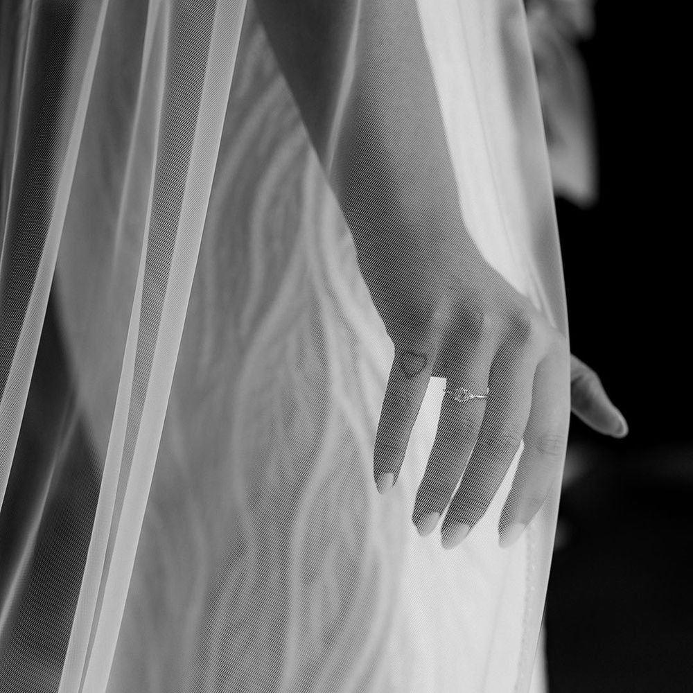 Bride with neutral colour wedding nails with simple diamond wedding ring wearing a cathedral length veil 