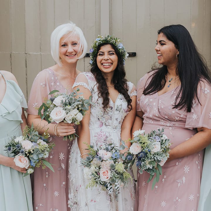 Bridal party in mismatched bridesmaid dresses holding pastel wedding bouquets 