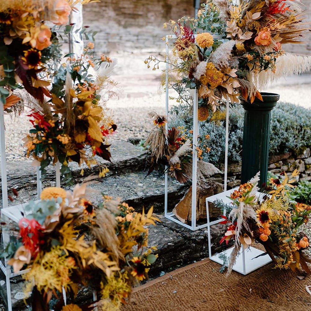 Dried autumnal wedding flower display at the alter of Broadfield Court with sunflowers, garden roses, pampas grass, eucalyptus, yellow tall kangaroo paws, orange osmanthus flowers, foliage and dried flowers 
