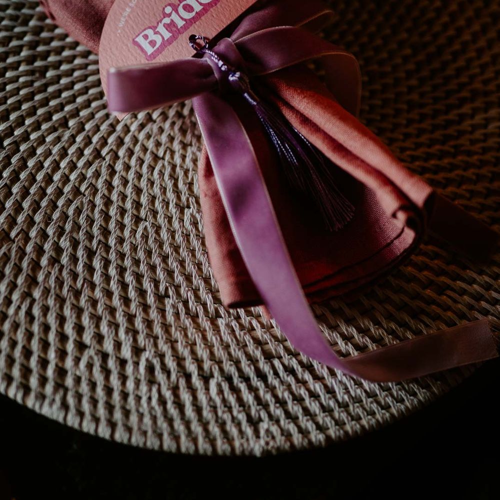 Dusky pink wedding napkin tied with purple ribbon and pink retro semicircular wedding place name 
