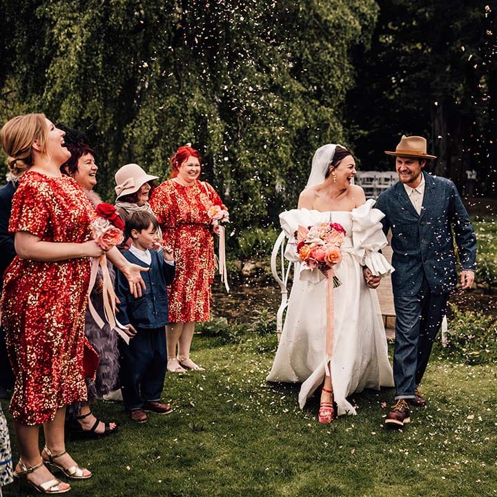 Bride in Jesus Peiro wedding dress walking with the groom in a double denim suit to confetti 