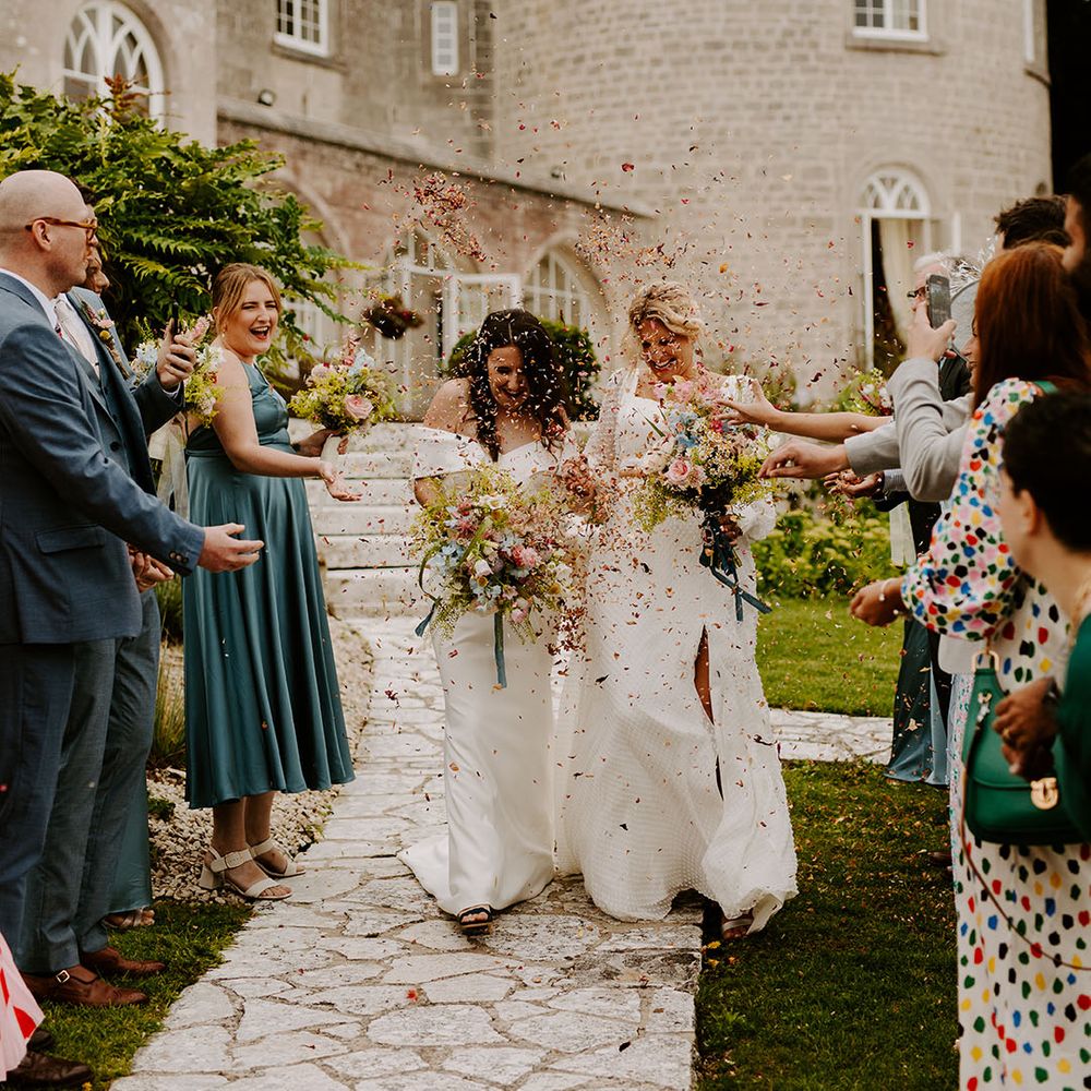 Confetti exit with dried petals for two brides at castle wedding venue in Dorset 
