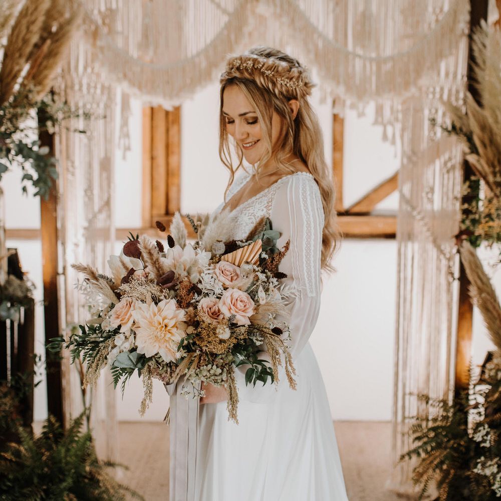 Bride holding blush pink bridal bouquet with macrame backdrop and fishtail plaited hair 