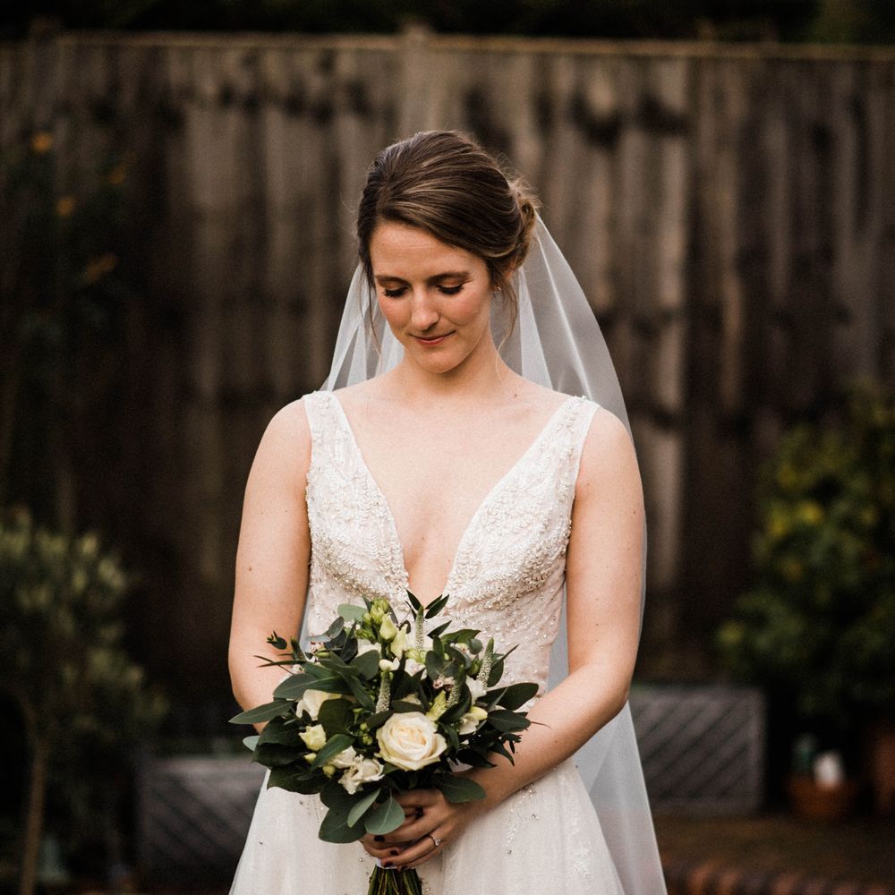 Bride looks down as she holds classic floral bouquet