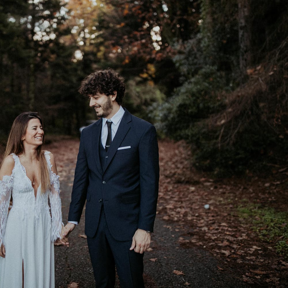 The bride and groom walking through the woodland together