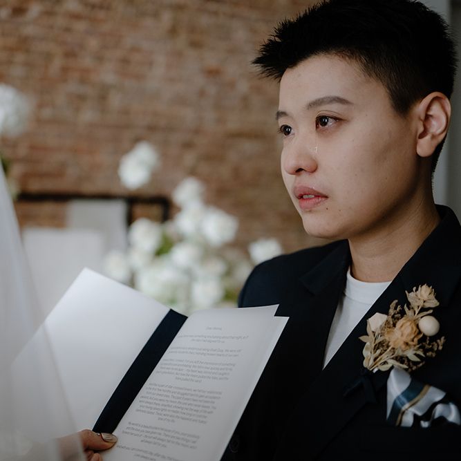 Emotional Asian Lesbian wedding ceremony with bride in navy jacket crying during the vows 