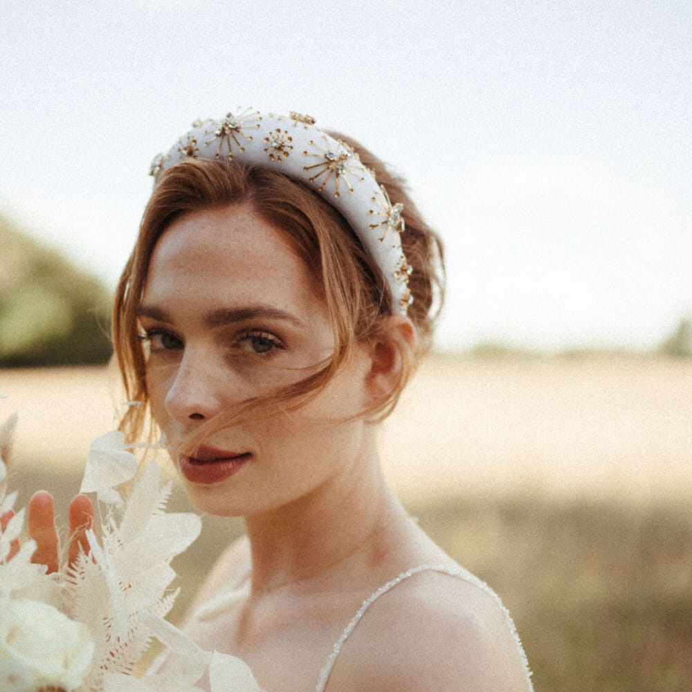 Bride wearing a white and gold beaded headband with all white flower bouquet