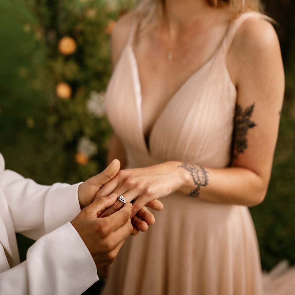 Bride putting a diamond wedding ring on her brides finger 