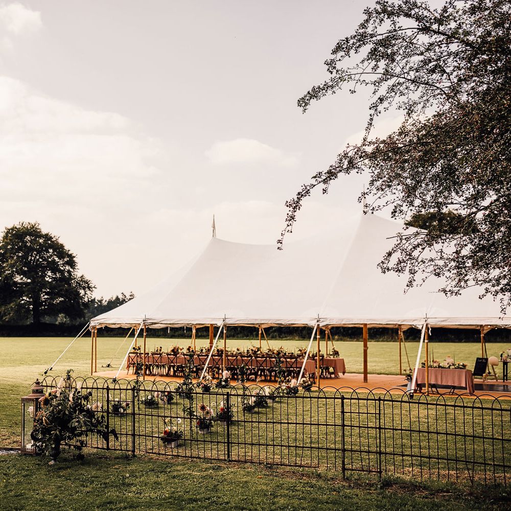 Garden marquee wedding reception with white open sided tent, long dusky pink tables, florals and candles for Cornish wedding
