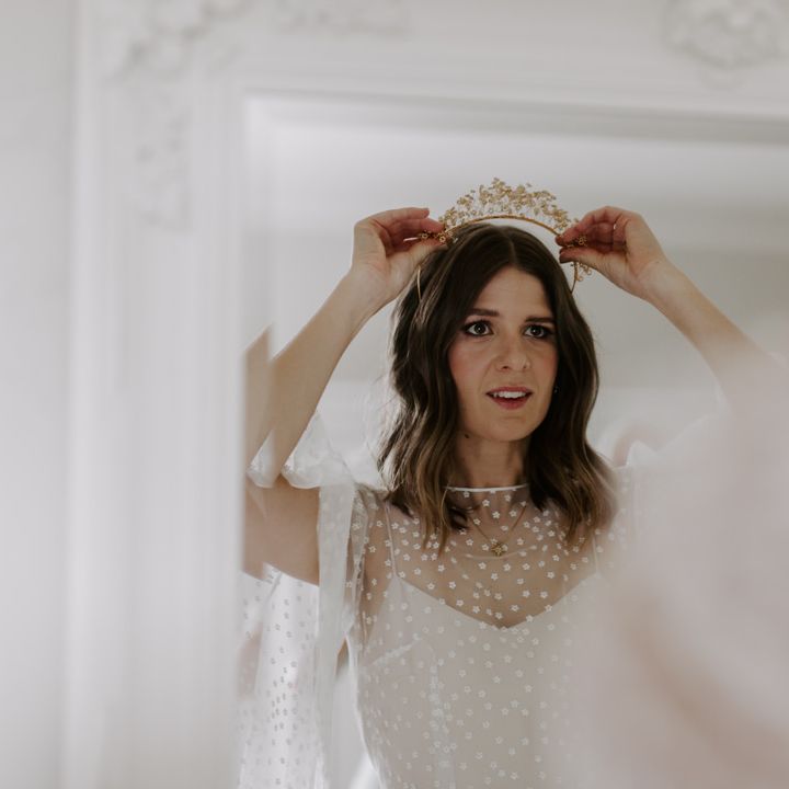 Bride places crown in her hair on her wedding day