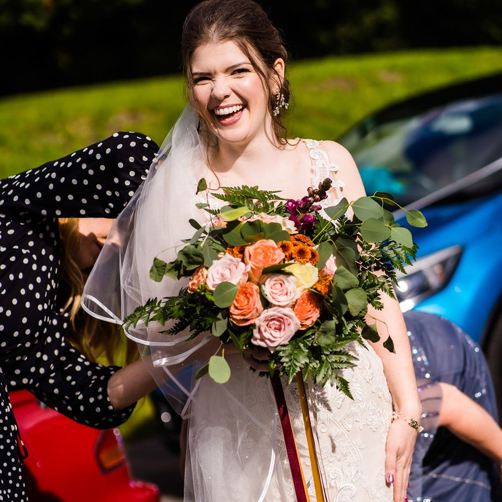 Bride in lace mermaid wedding dress with colourful wedding bouquet, pink wedding nails and leaf jewellery