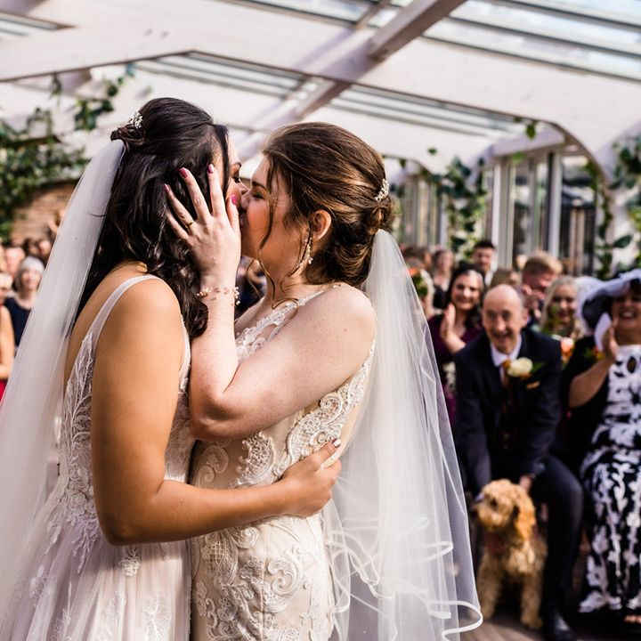 Brides share their first kiss as a married couple as wedding guests applaud