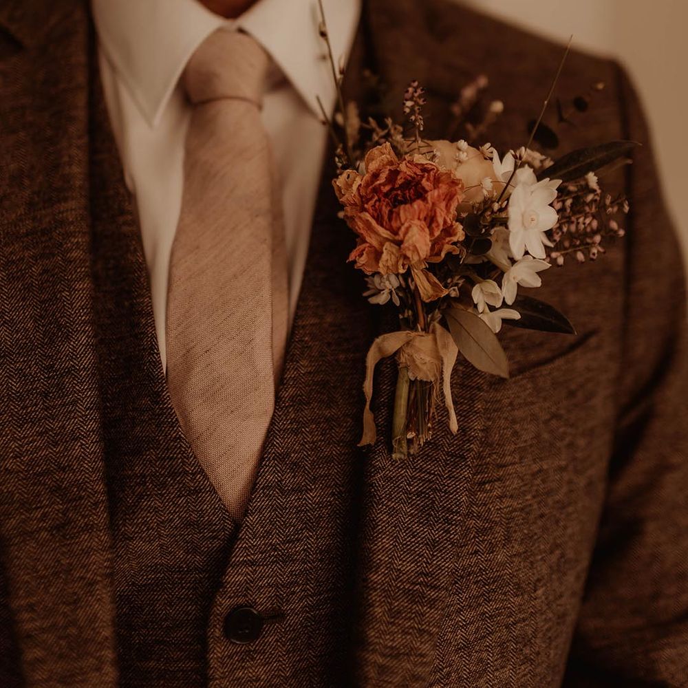 Father of the bride in brown suit, neutral tie and autumnal coloured buttonhole flowers 