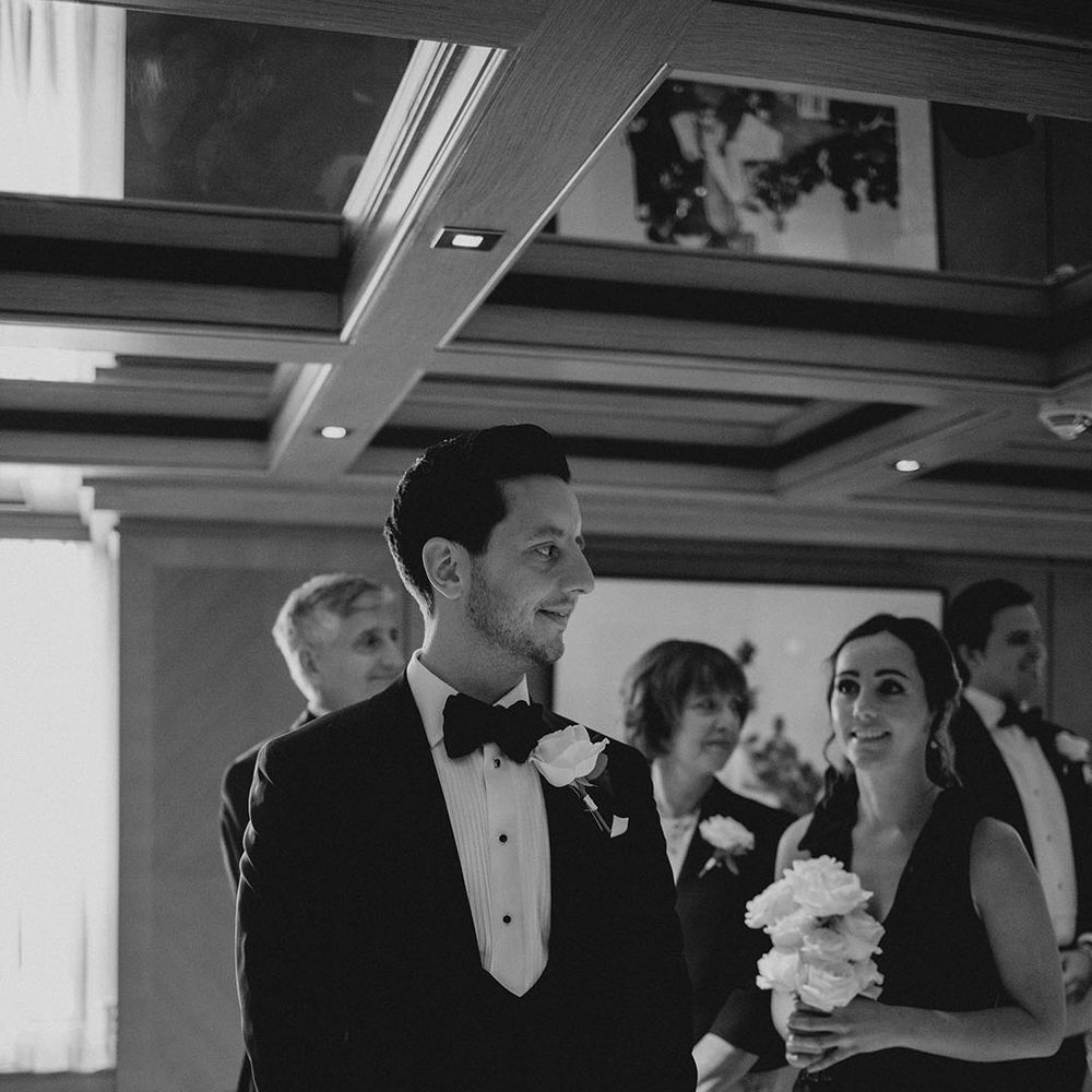 Groom in black tie turns as he sees the bride for the first time 