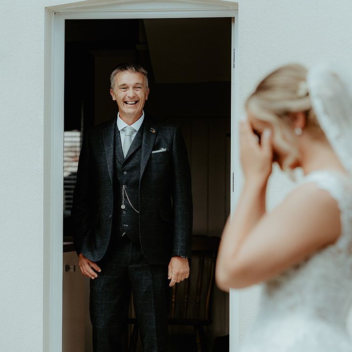 Father of the bride smiles brightly as he gets the first look at the bride in her wedding dress
