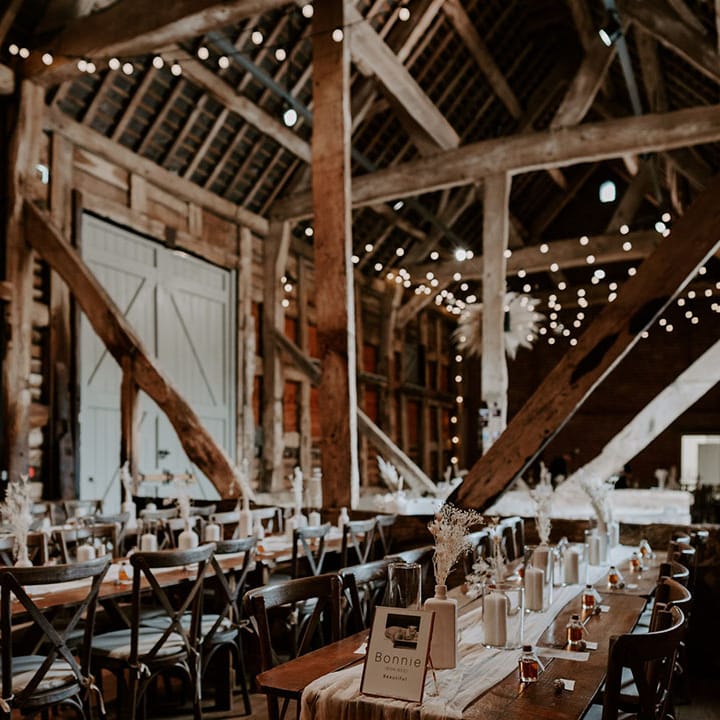 Pimhill Barn rustic wedding venue with neutral minimal styling including lots of white pillar candles, table runners, dried flowers and pampas grass