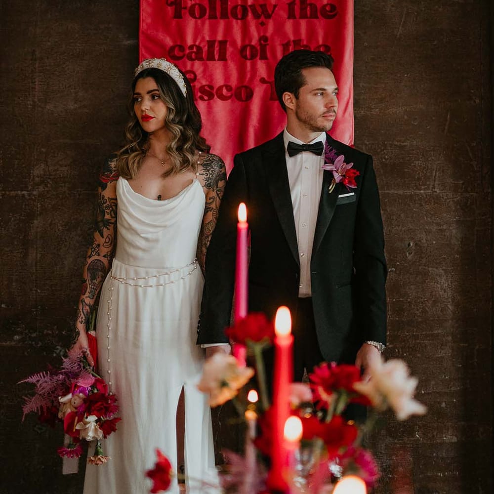 Bride and groom standing behind large viva magenta fabric wedding banner 