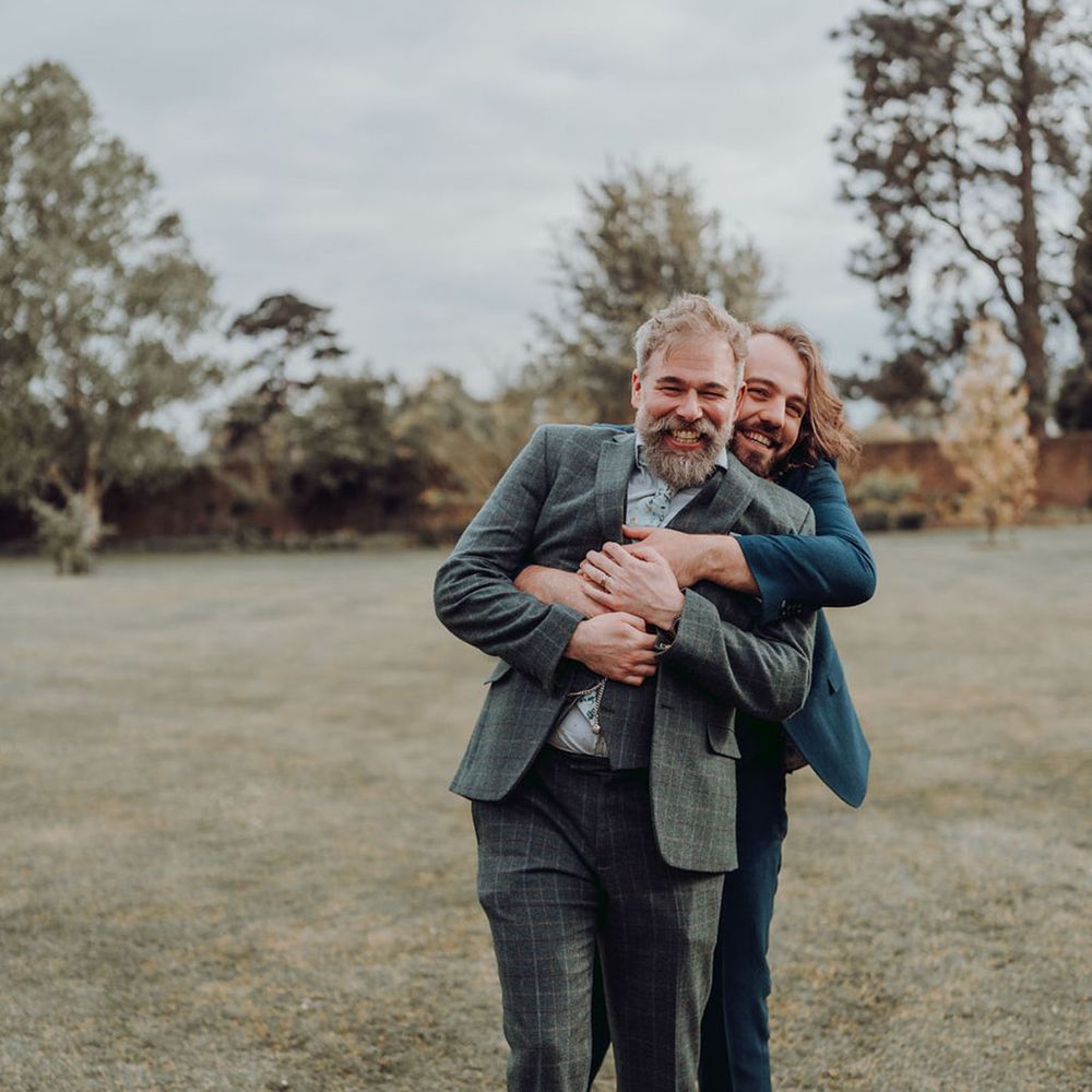 Queer grooms embrace outdoors for couples portraits in Kew Gardens for botanical wedding 
