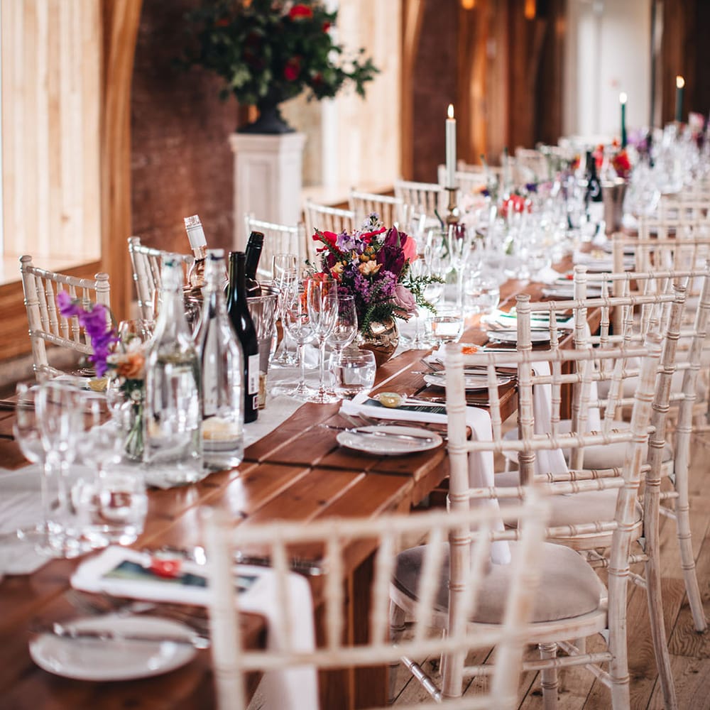 Romantic wedding tablescape with dark green candles in gold candle holders and pink and purple wedding flower arrangement decor 