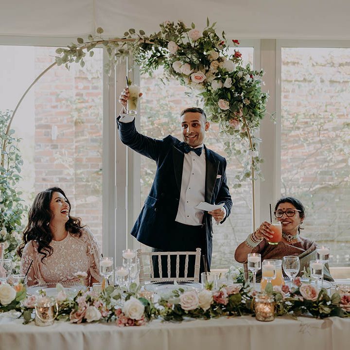 Groom gives wedding speech and lifts glass in the air at Braxted Park wedding venues Essex