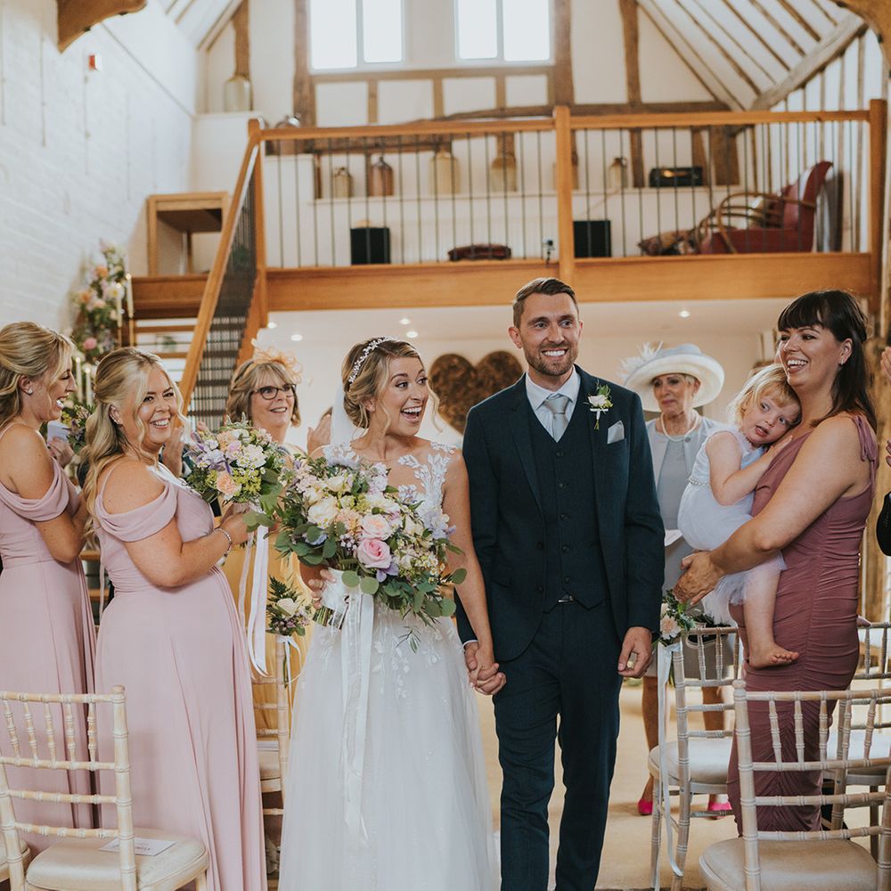 The bride and groom walk back down the aisle as a married couple at Dove Barn for their rustic wedding 