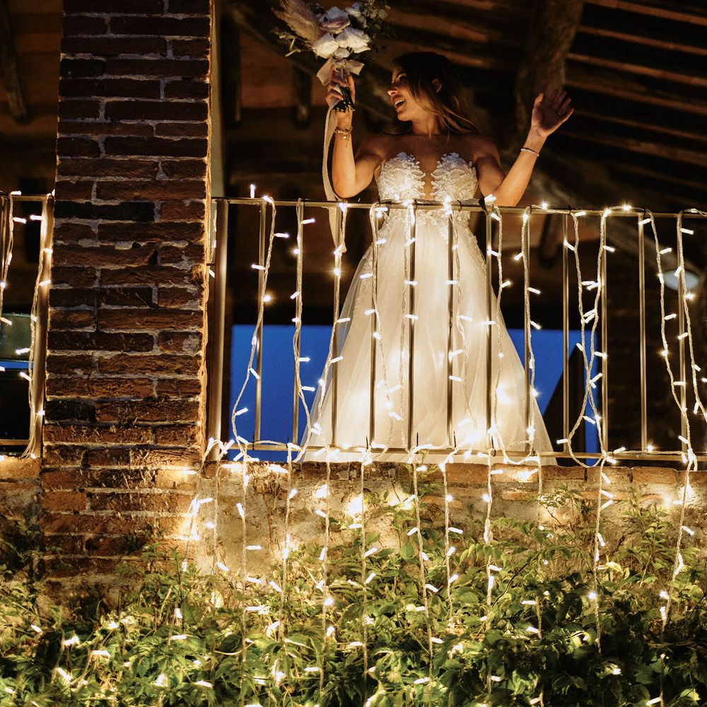 Bride preparing for bouquet toss on balcony with fairy lights wedding lighting