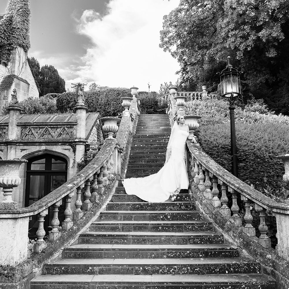 Bride in strapless mermaid Pronovias wedding dress standing on the stairs with statement veil 