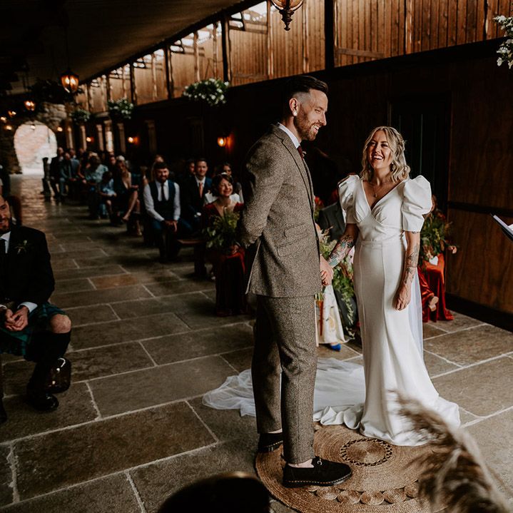 Bride in puff sleeve wedding dress with the groom in a grey tweed suit 