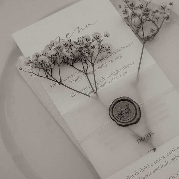 Simple monochrome wedding place setting with white stationery and personalised wax seal 