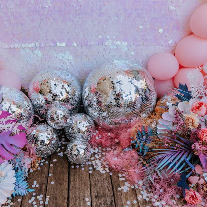 Holographic pastel wedding decor with sequin backdrop, disco balls and coloured monstera leaves