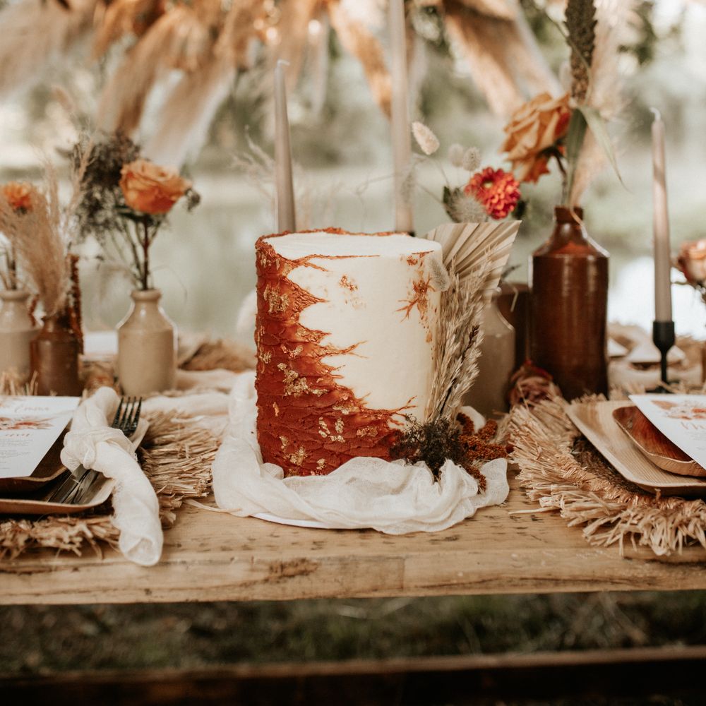 Wedding cake with burnt orange and white frosting complete with gold leaf decor 