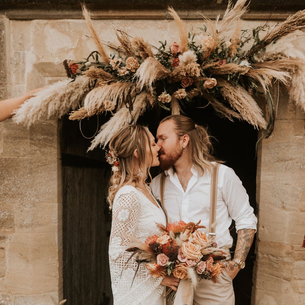 Bride & groom kiss surrounded by floral decoration 