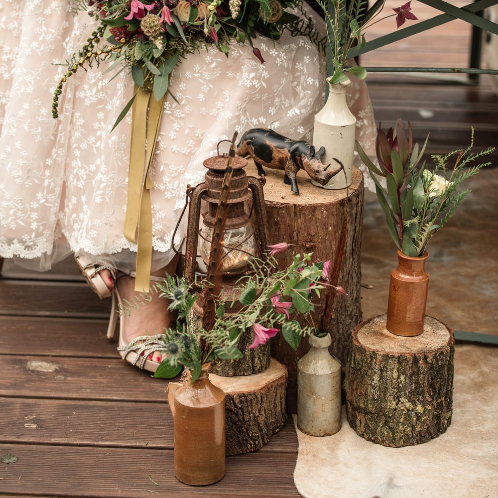 Bride sits at wooden table holding floral bouquet with pink blooms