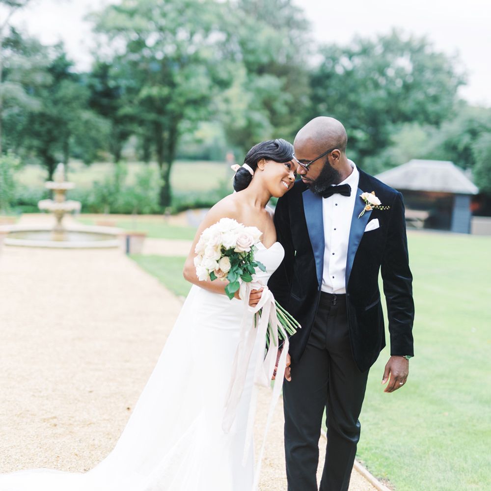 Classic bride in a strapless wedding dress holding a rose bouquet as she leans on her grooms shoulder in a black tuxedo 