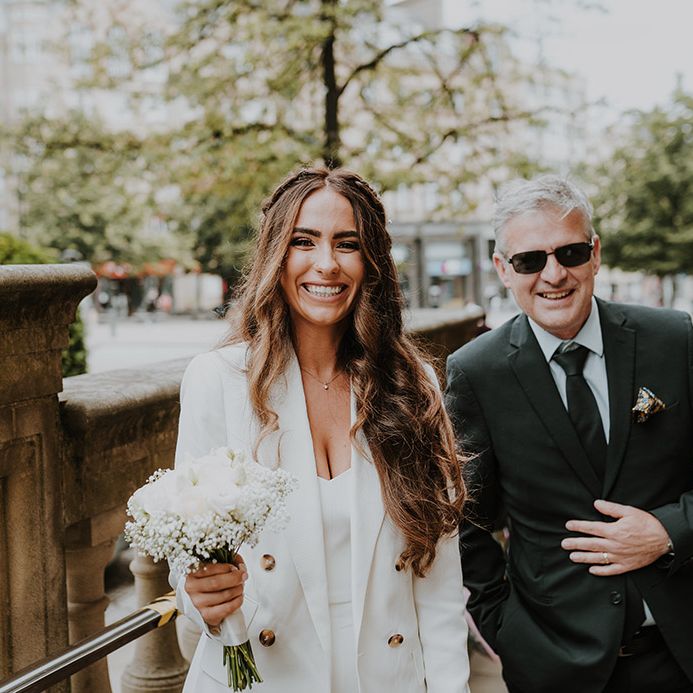 Beautiful bride with long wavy hair in a white blazer, camisole and trousers