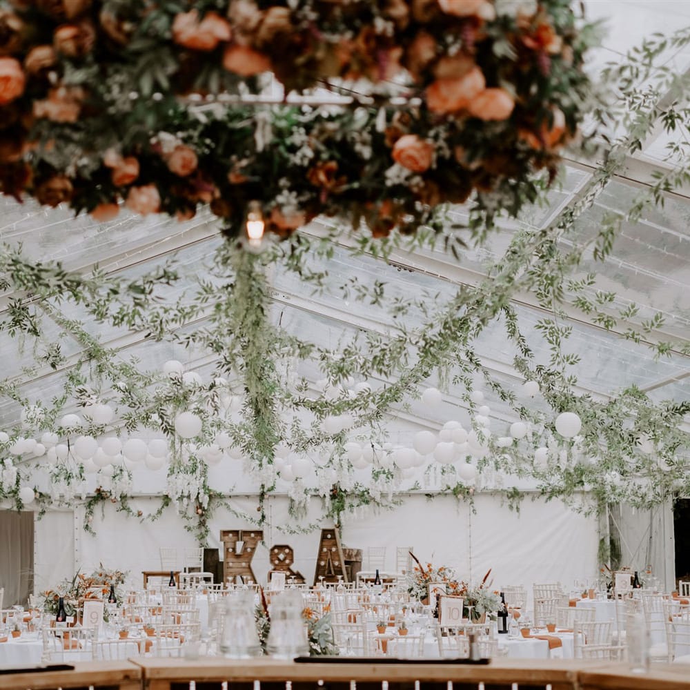 Interior of wedding reception marquee with clear roof, white ball lights and garlands for DIY garden wedding in Bedfordshire