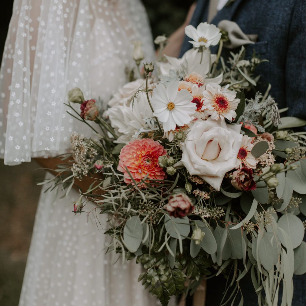Bride holds floral bouquet complete with green foliage