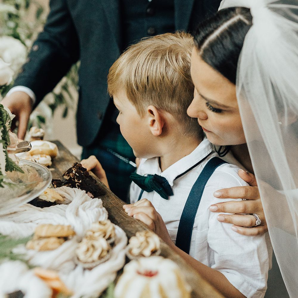Bride, groom and son looking at the dessert table at their luxury English micro wedding 