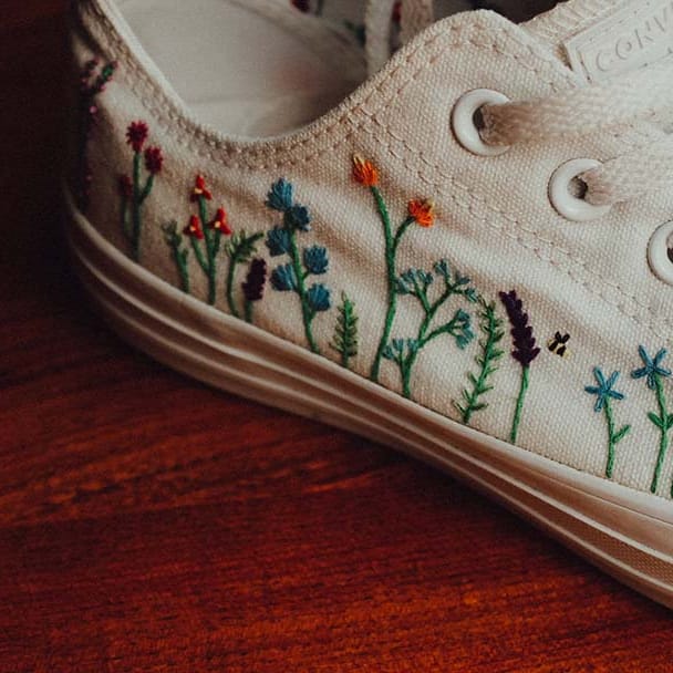 Bride wears custom white converses with colourful stitched flowers on the sides