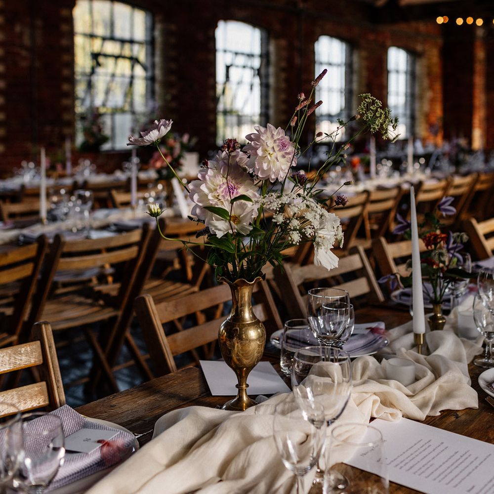 Wedding table centrepiece with flower stems in a gold vessel 