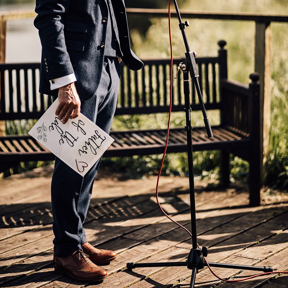 Father of the bride in blue suit and sunglasses reads out his wedding speech 
