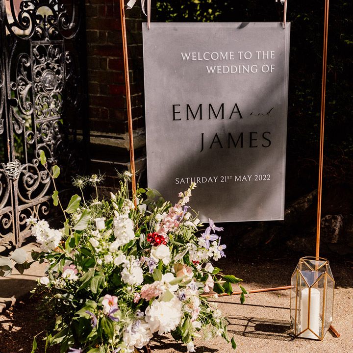 Frosted welcome wedding sign on copper frame with candle in geometric lantern and pink and white wedding flowers 