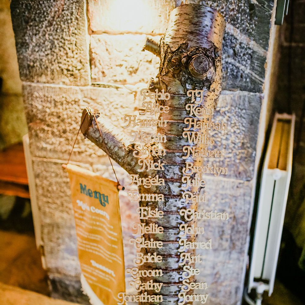 Tree trunk table plan complete with wooden names alongside hanging fabric menu banner 