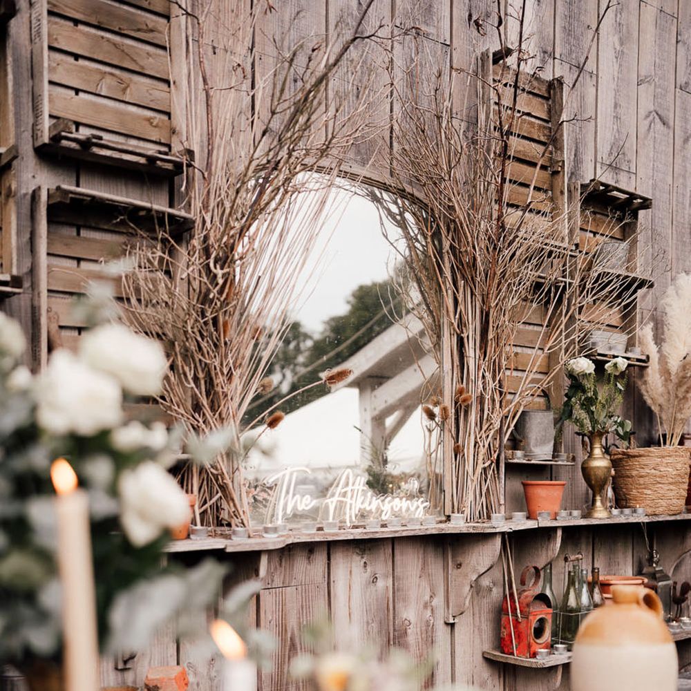 Outdoor mirror surrounded by branches and a customised neon sign with the couple's new last name