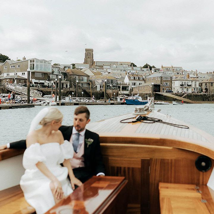 Bride & groom ride across the sea in boat during Salcombe wedding 