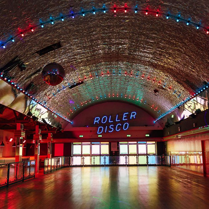 Large roller disco hall at Margate Dreamland with colourful windows, a large disco ball and colourful fairy lights 