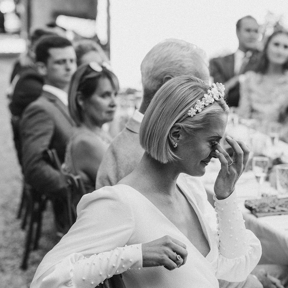 emotional bride in a flower headband and long sleeve wedding dress with pearl cuff embellishments 