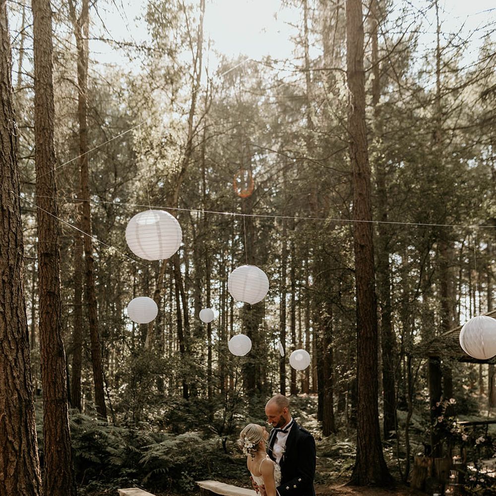 Camp Katur wedding venue in Yorkshire with white paper lanterns and fairy lights decorating the woodland ceremony space 