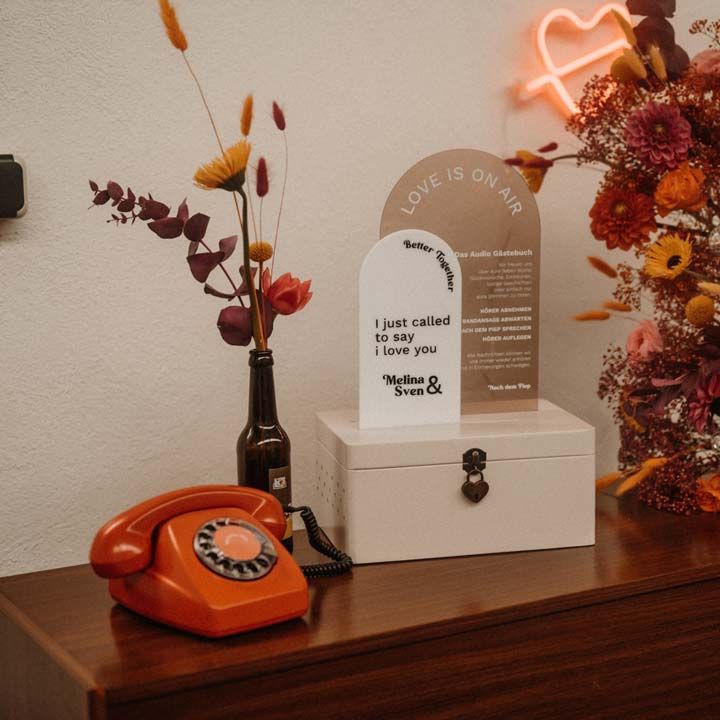 Red wedding audio guest book, retro semicircular wedding signs, large red, orange and pink vibrant wedding floral arrangements at German editorial shoot with vinyl wedding arch
